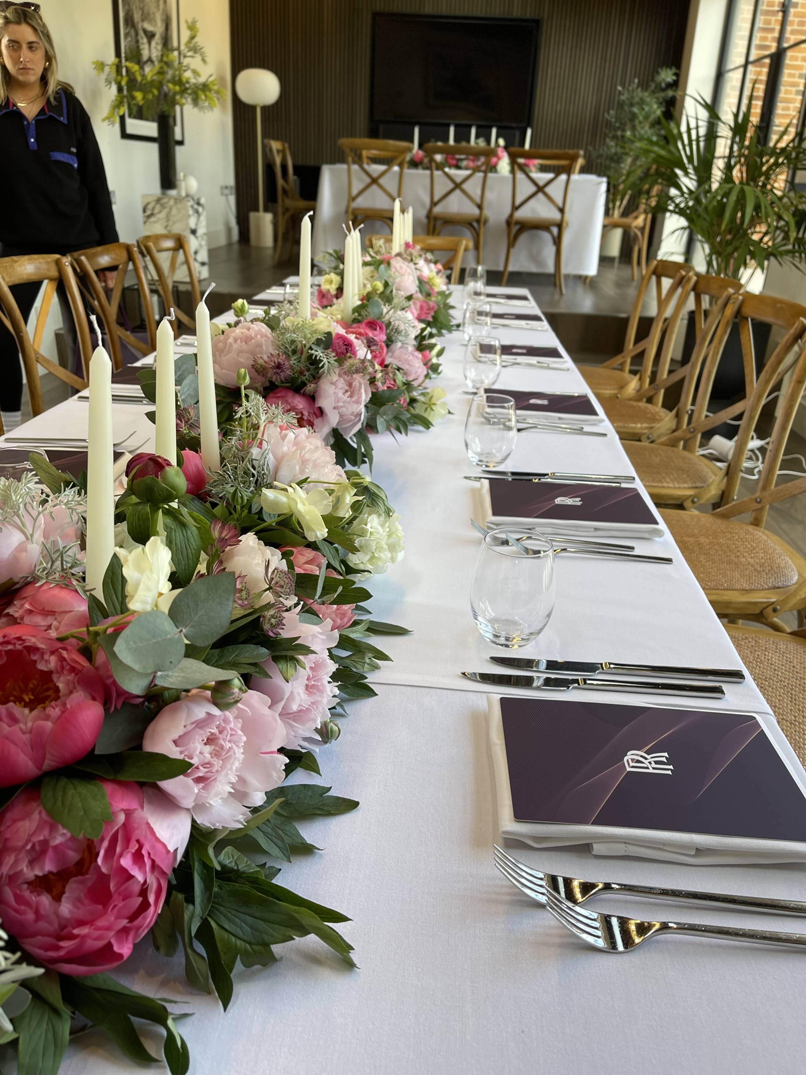 Pink and white flowers along a dinner table with Rolls-Royce menus