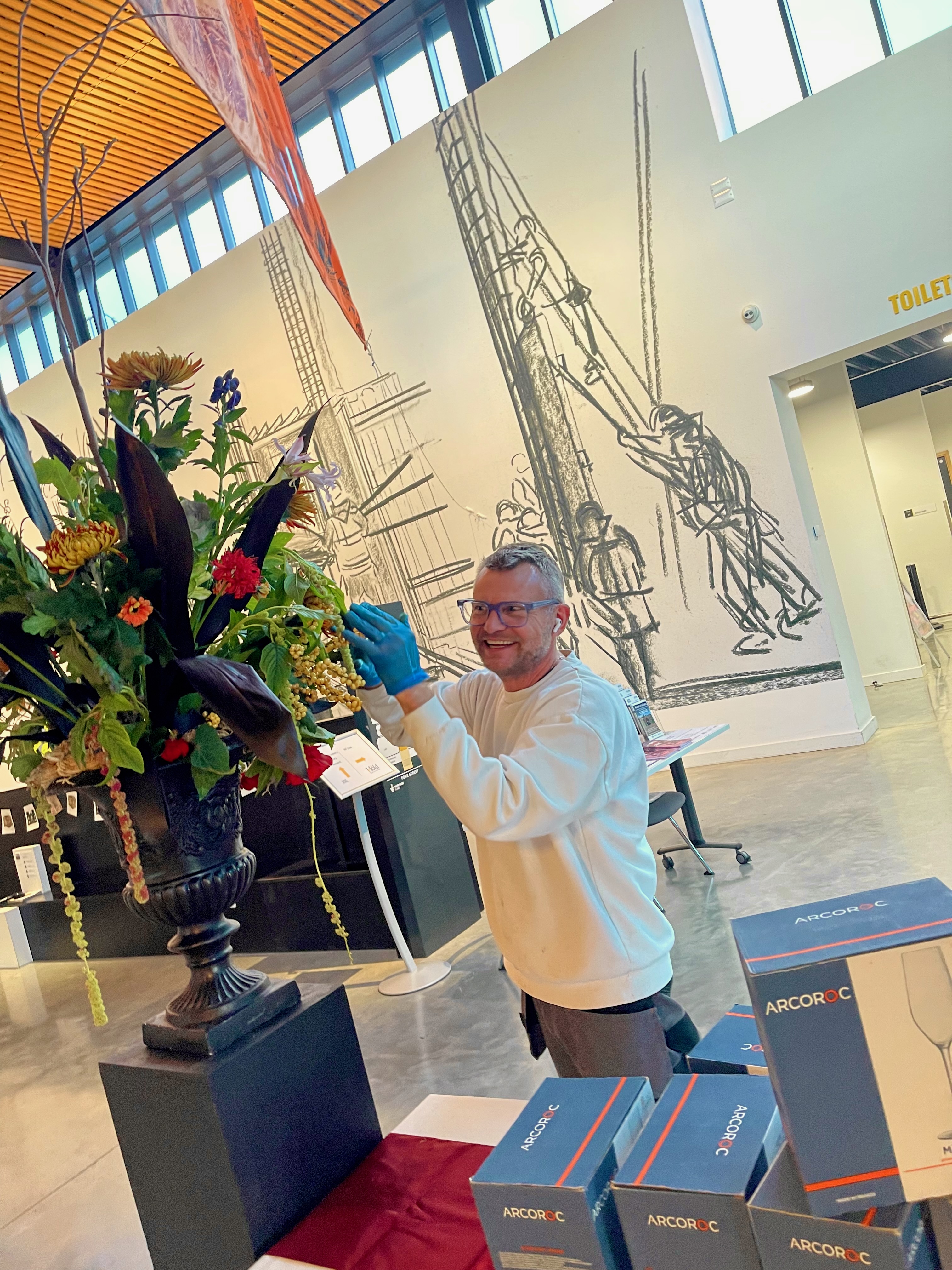 Michael Pooley placing flowers in a large urn arrangement at The Hold