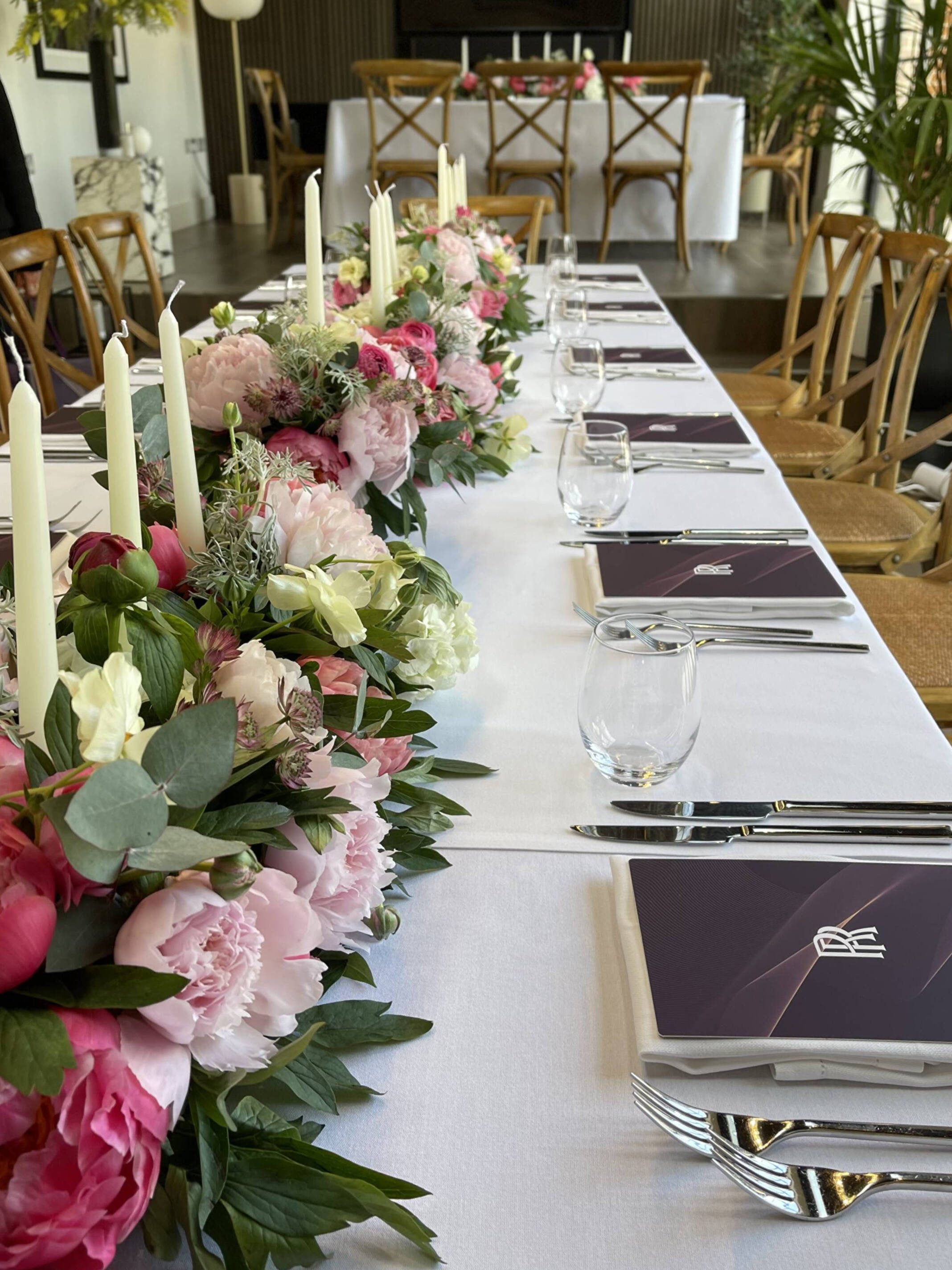 Peonies and candles along a private dinner table with Rolls-Royce menus at each place