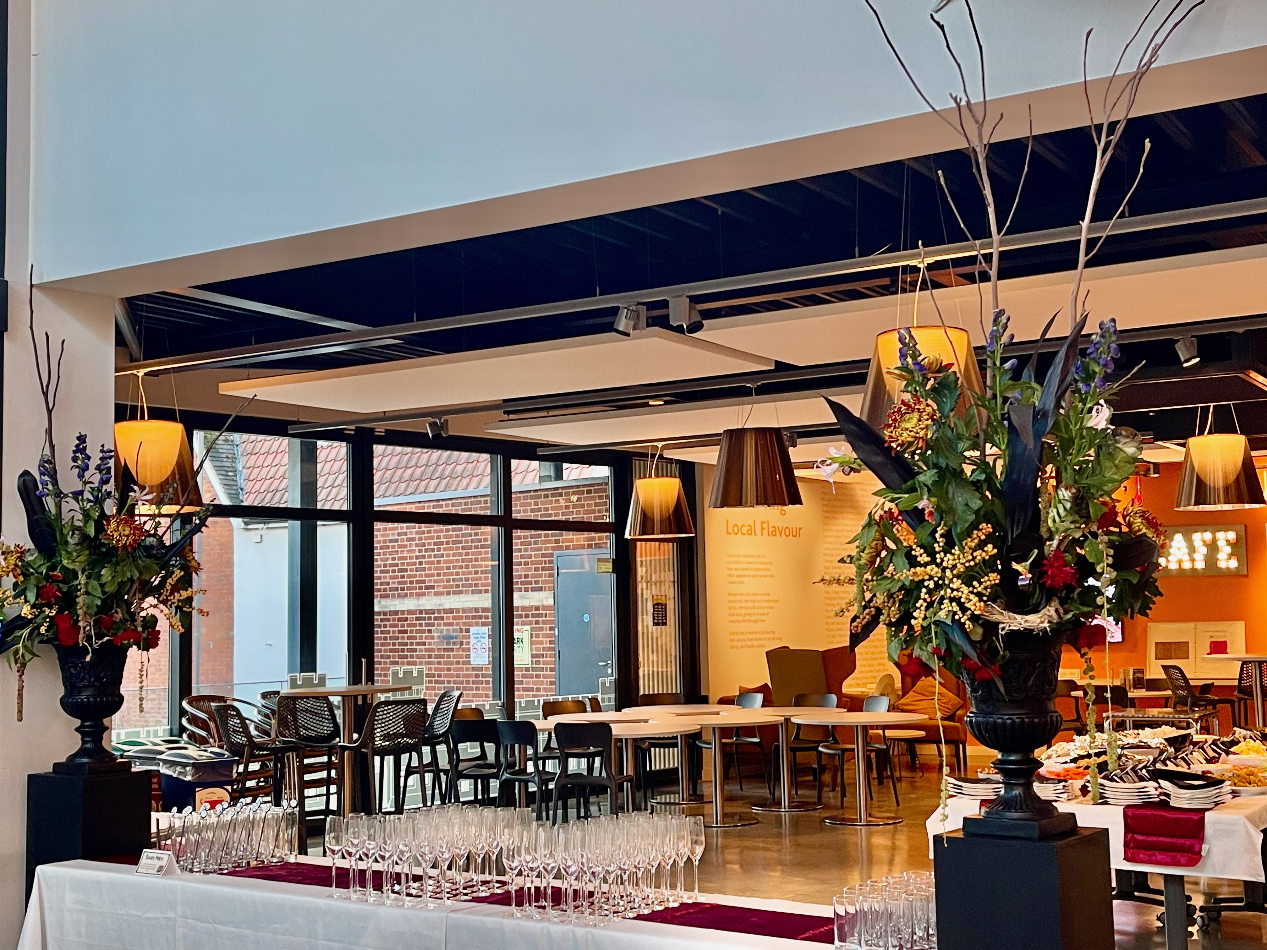 Two generous floral urns on plinths framing the reception space at The Hold