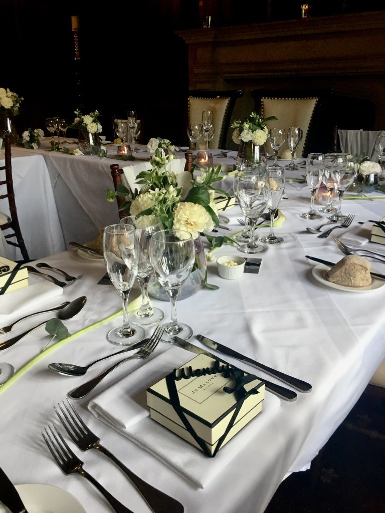 White and green flowers in glass vases along an elegantly set dinner table