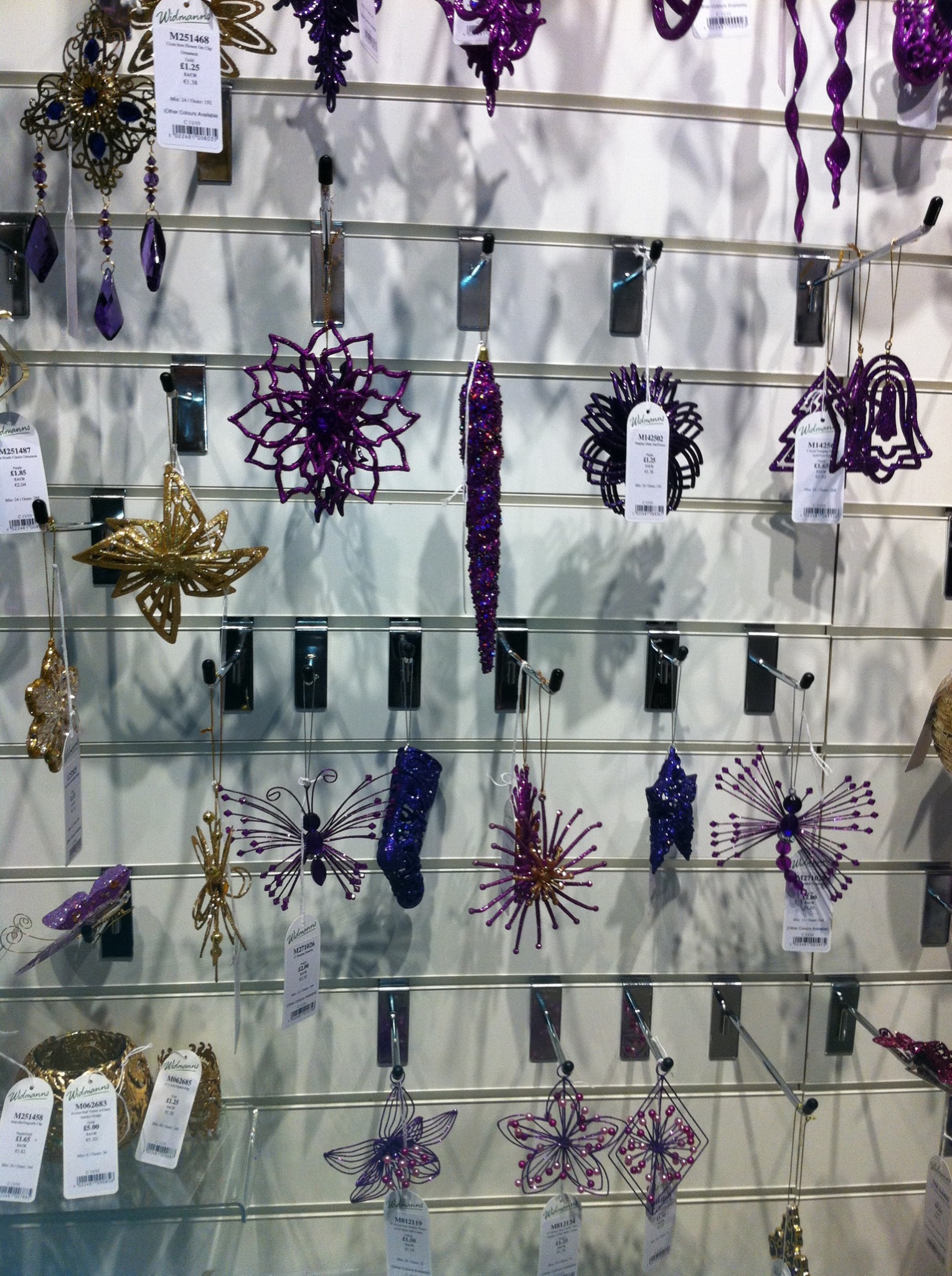 Purple and gold decorative ornaments arranged on a retail display wall