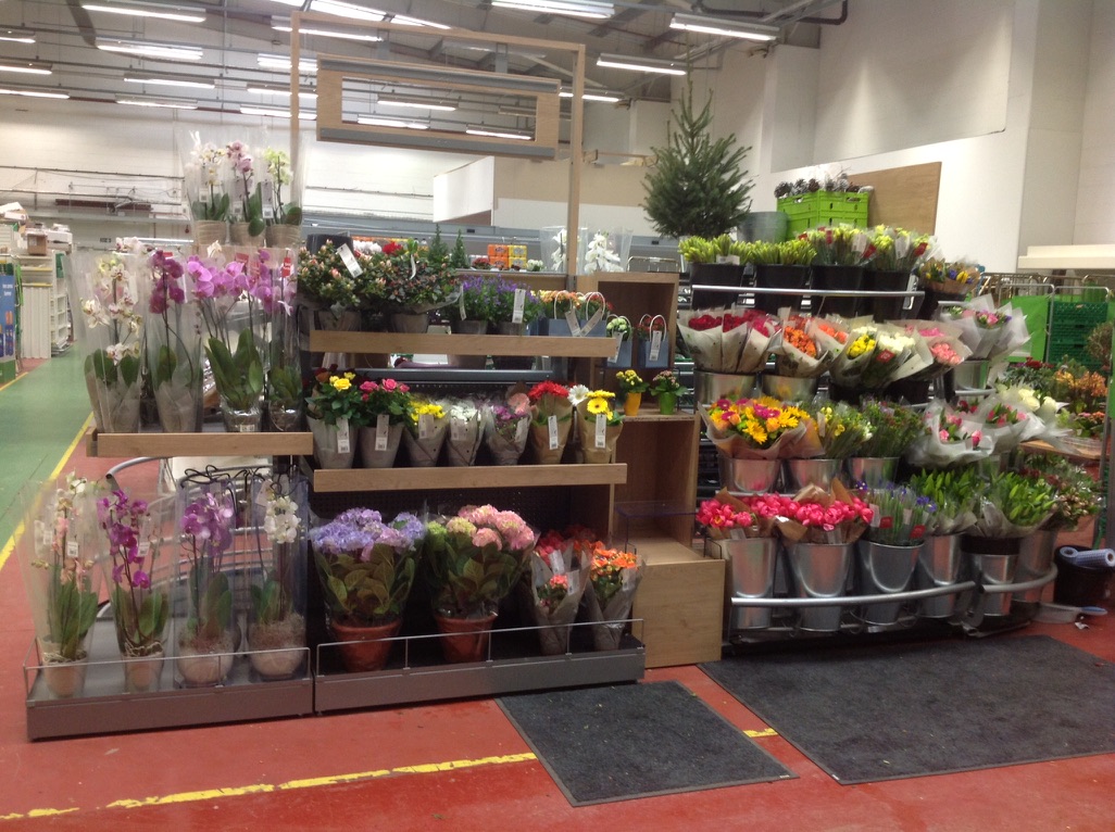 Waitrose flower and plant merchandising display with orchids, hydrangeas and bouquets arranged across tiered stands