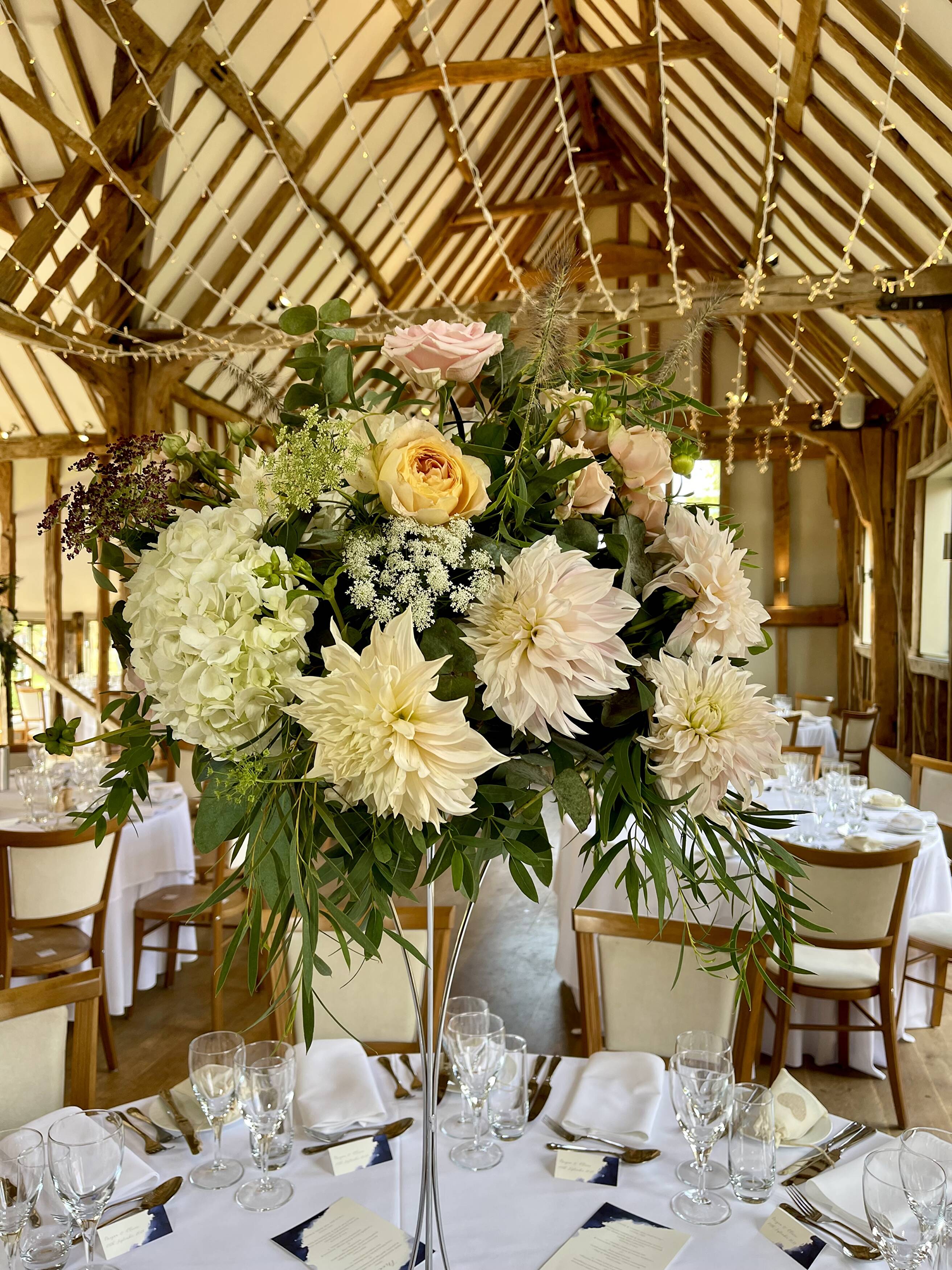 Pale Cafe au Lait dahlias in a tall arrangement beneath the timber beams at Easton Grange