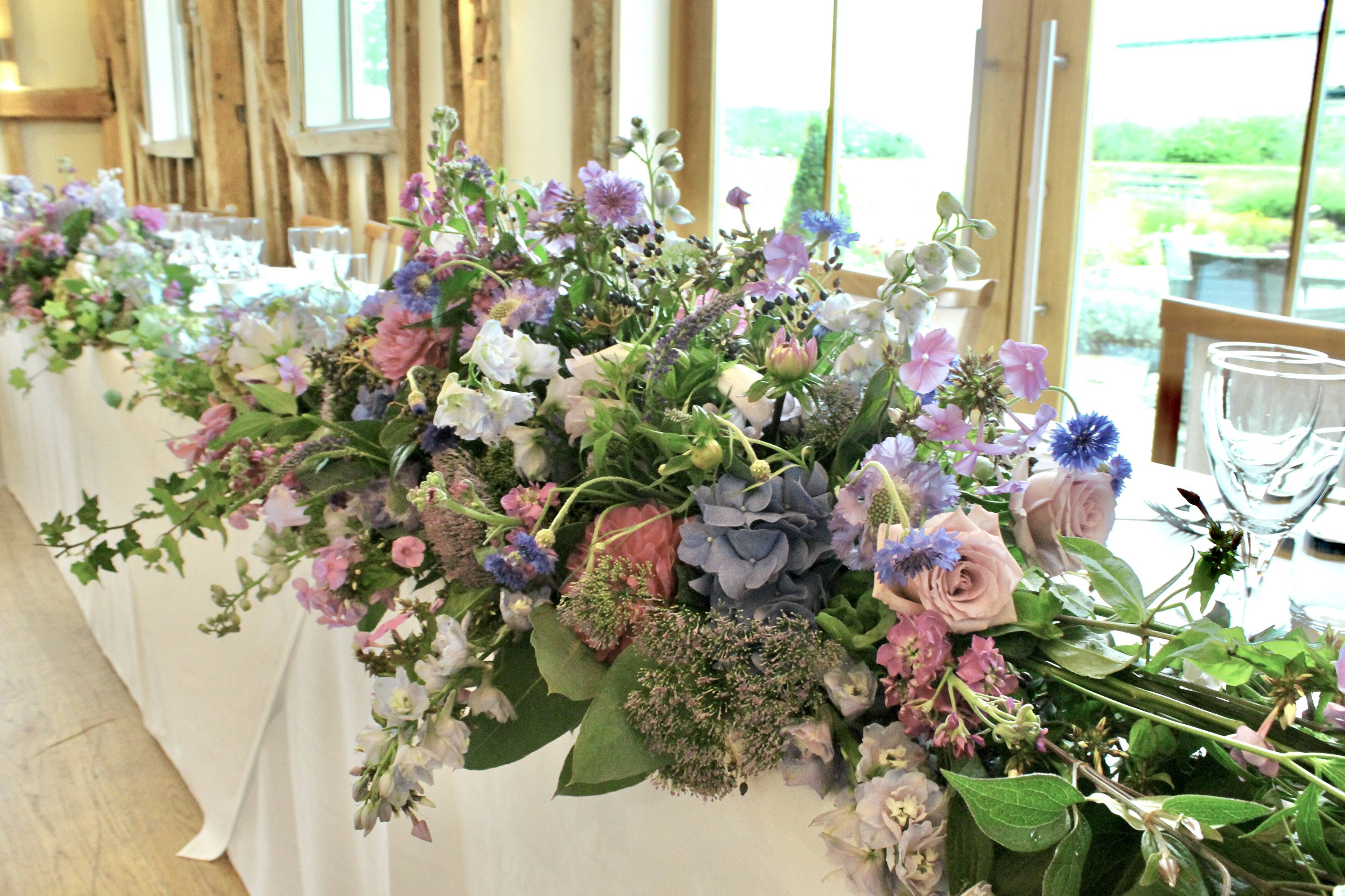 A generous arrangement of pastel wedding flowers along a reception table at Easton Grange