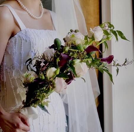 An overarm bridal bouquet with plum callas and pale flowers