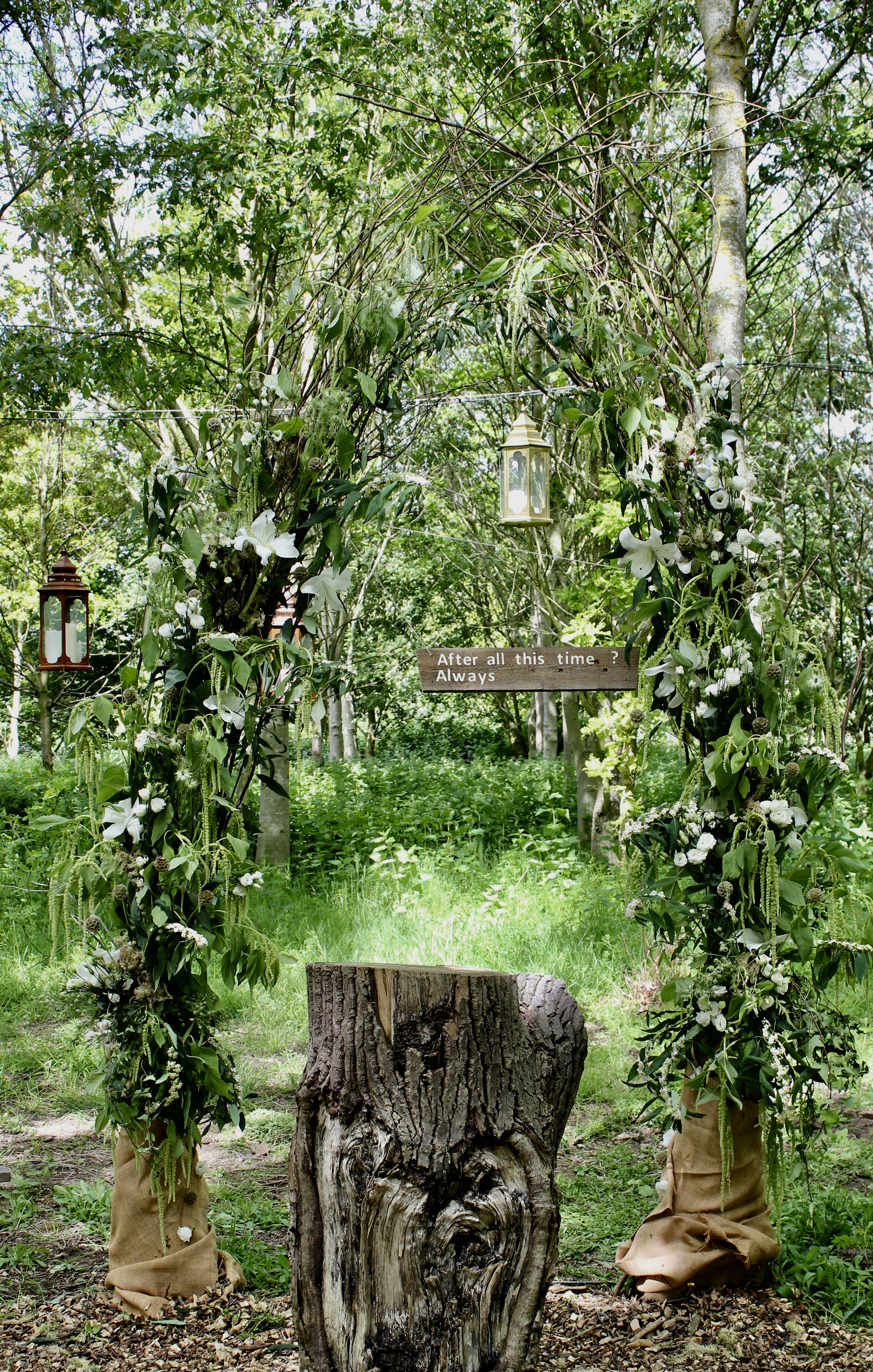 A woodland ceremony arch made with green foliage and white flowers